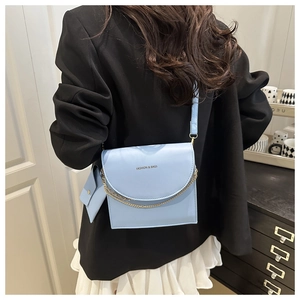 Detail of light blue crossbody bag with gold chain and matching mini pouch on a model