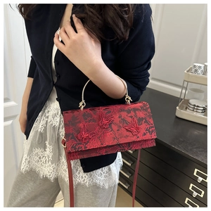 Detail of red floral lace embroidery and three-dimensional butterfly patches on bag