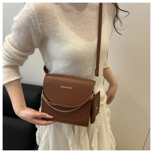 Detail of brown faux leather crossbody bag with metal chain trim and small coin purse