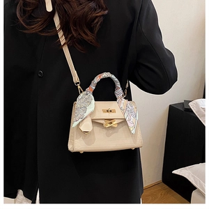 Close-up of off-white crocodile embossed Kelly handbag with silk scarf wrapped handle