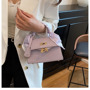 Close-up of light purple crocodile texture handbag with gold lock and silk scarf handle