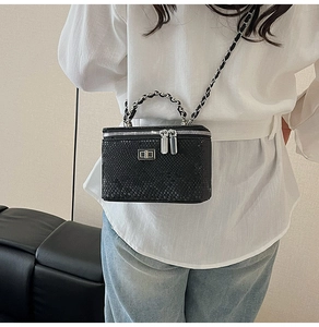 Detailed macro view of black snakeskin texture and silver chain strap on crossbody bag