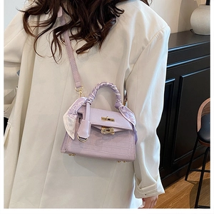 Detail of lavender crocodile-embossed Kelly bag with silk scarf on handle and gold buckle