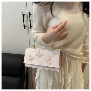 Detailed shot of lace texture and pink 3D butterfly appliques on a chic handbag