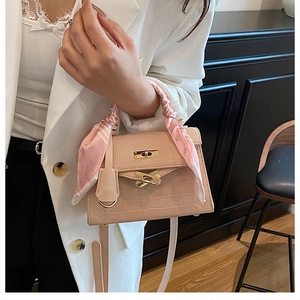 Detail of pink croc-embossed Kelly bag featuring gold hardware and silk scarf on handle