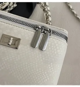 Detail of silver dual zippers and snakeskin texture on white chain shoulder bag