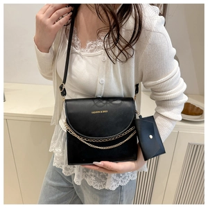 Detail of matte leather crossbody bag with dual gold chains and a mini pouch attachment