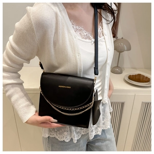 Detail of a black square crossbody bag with gold chain and Fashion & Bags text on model