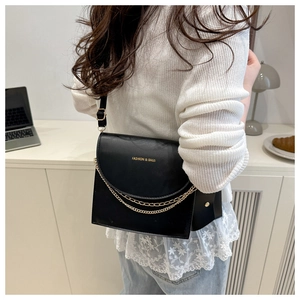 Detail of a vintage black leather crossbody bag with dual gold chain and fashion lettering