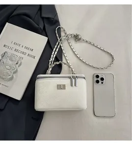 Detail of white snakeskin texture crossbody bag with silver chain strap and dual zippers