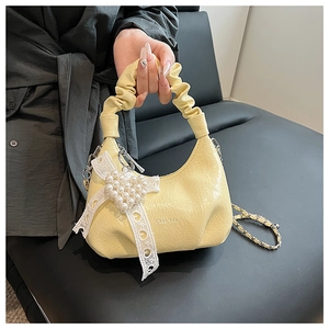 Detail of yellow pleated cloud bag with pearl heart charm and lace ribbon handle