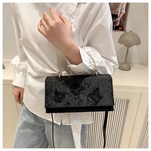 Macro view of black jacquard fabric with three-dimensional butterfly embroidery on bag