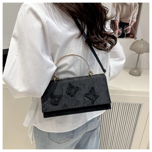 Close-up of black lace handbag featuring 3D butterfly embroidery and golden metal handles