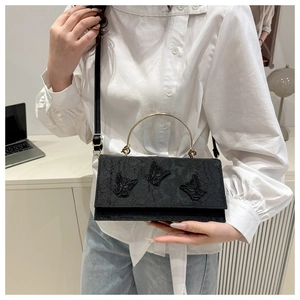 Detail of black lace crossbody bag with butterfly appliques and gold ring handle