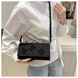 Close-up of black lace crossbody bag with gold handle and 3D butterfly embroidery