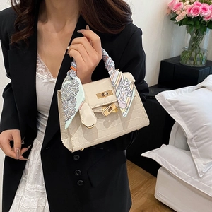 Elegant cream crocodile pattern Kelly style handbag with scarf handle shown on a model