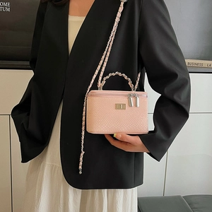 Pink snake pattern chain box bag worn by a model in a black suit and white skirt
