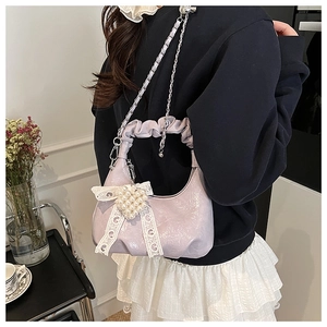Close-up of lavender pleated handbag with glossy finish and pearl lace pendant charm