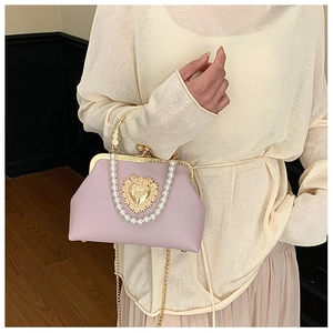 Detailed view of lilac pearl shell bag with golden heart relief and metal frame clasp