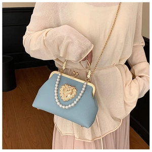 Detail of light blue shell bag with pearl handle, heart crystal and gold clasp closure
