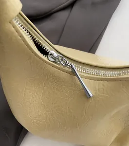Close-up of silver metal zipper and pleated texture on yellow faux leather cloud bag