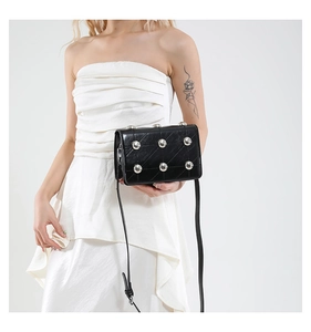 Detail of punk crossbody bag with silver dome studs and quilted leather on a model