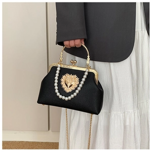 Detail of vintage black shell bag featuring pearl chain and gold heart metal buckle