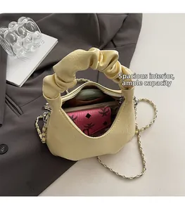 Detail showing spacious interior of yellow pleated handbag with phone and makeup accessories