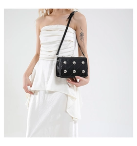 Close-up of black quilted shoulder bag featuring oversized silver studs and metallic details