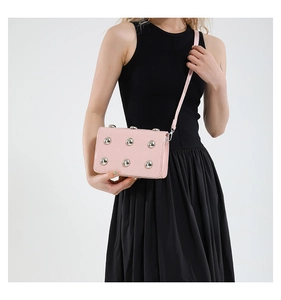 Detail of pink punk crossbody bag with silver studs and quilted faux leather texture