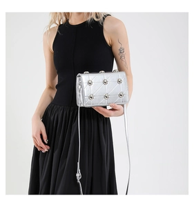 Silver quilted crossbody bag with spherical studs shown on a model in a minimalist style