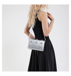 Detail view of silver quilted crossbody bag with large metallic rivets on the flap