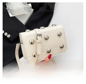 Close-up of cream crossbody bag with silver rivet details and diamond quilted stitching
