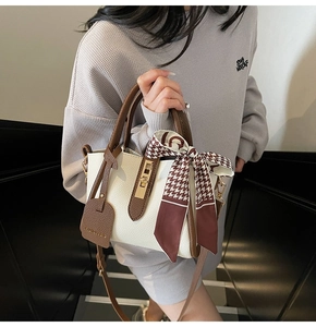 Dettaglio della borsa a secchiello bicolore bianco e marrone con foulard di seta a contrasto