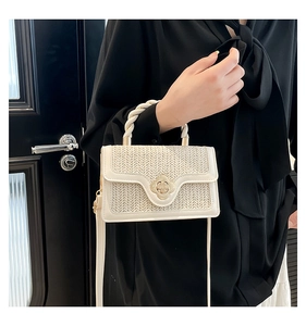 Detail of woven white handbag with a gold flower buckle and twisted rope top handle