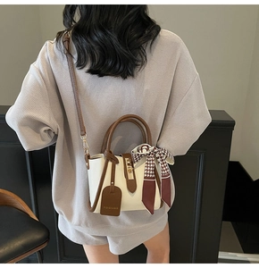Dettaglio mini borsa a tracolla con foulard di seta, manici tondi e ciondolo moda