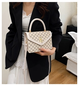 Detail of beige monogram handbag with M-pattern and elegant gold metal buckle hardware