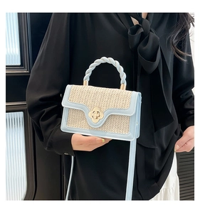 Dettaglio del manico in pelle blu e chiusura a fiore dorato su borsa in tessuto