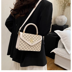 Close-up of beige monogram crossbody bag with golden twist lock and V-cut flap design
