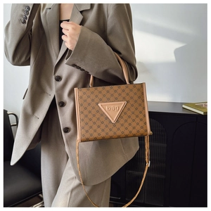 Detail of vintage brown patterned tote bag held by a model in a gray suit