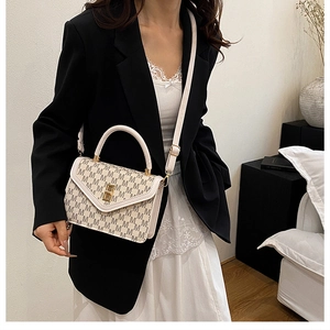 Close-up of cream handbag featuring M-letter monogram print and golden metal lock