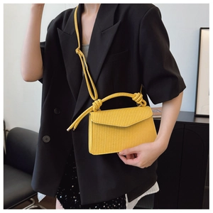 Détail du sac à main carré jaune tissé avec poignée nouée et bandoulière tressée chic