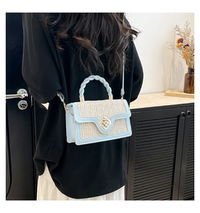 Dettaglio della chiusura a fiore dorato e trama intrecciata sulla borsa blu e beige