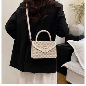 Detail of beige monogram handbag featuring gold twist lock and adjustable shoulder strap