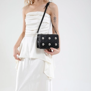 Chic black quilted punk bag with silver studs and adjustable strap worn by model