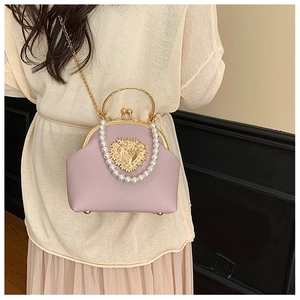 Detail of lavender shell bag with pearl handle and golden heart accessory on model