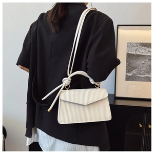 Détail du sac bandoulière blanc tissé avec ferrures dorées et poignée nouée élégante