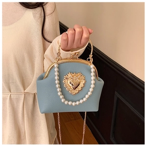 Detailed view of pearl handle and golden heart ornament on light blue shell bag