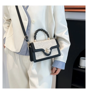 Detail of woven straw handbag with floral metal lock and black twist rope handle