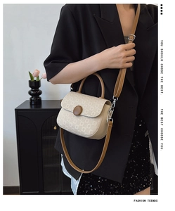 Detailed side view of beige textured handbag with brown handle and leather strap